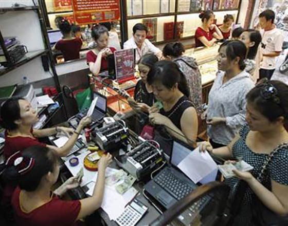 Employees count money as customers queue to buy gold at a Bao Tin Minh Chau gold shop in Hanoi. Photo by Reuters 
